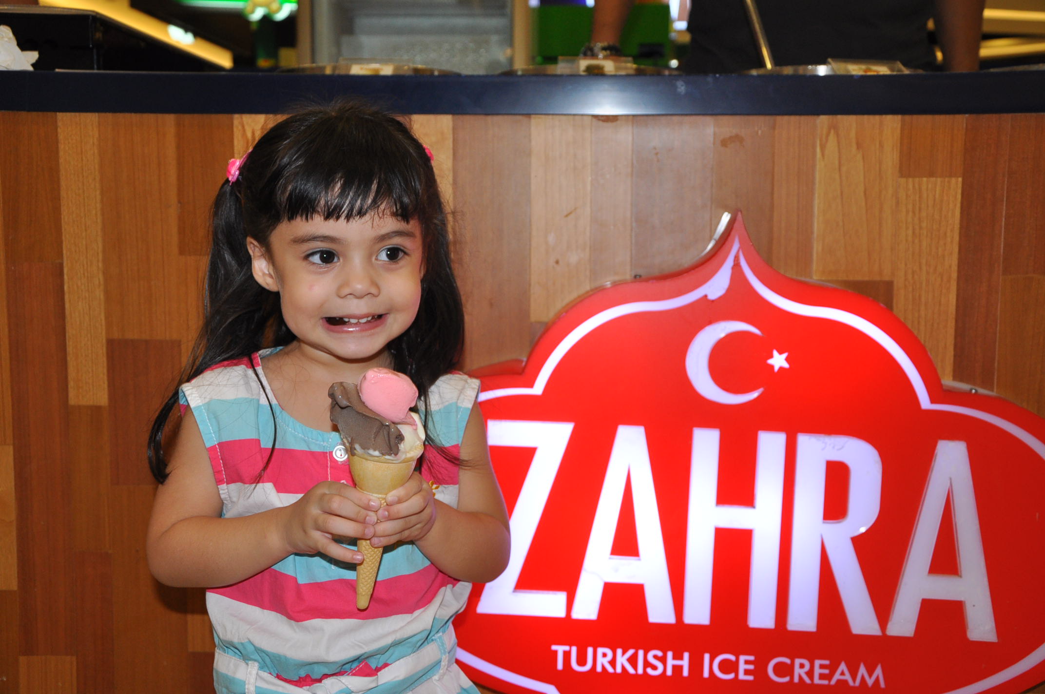 Smiling child holding Zahra ice cream cone
